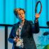 Image shows Judith Mcminn, Founder and CEO of Rezon, presenting about Rezon Halos® brain protection to an audience.